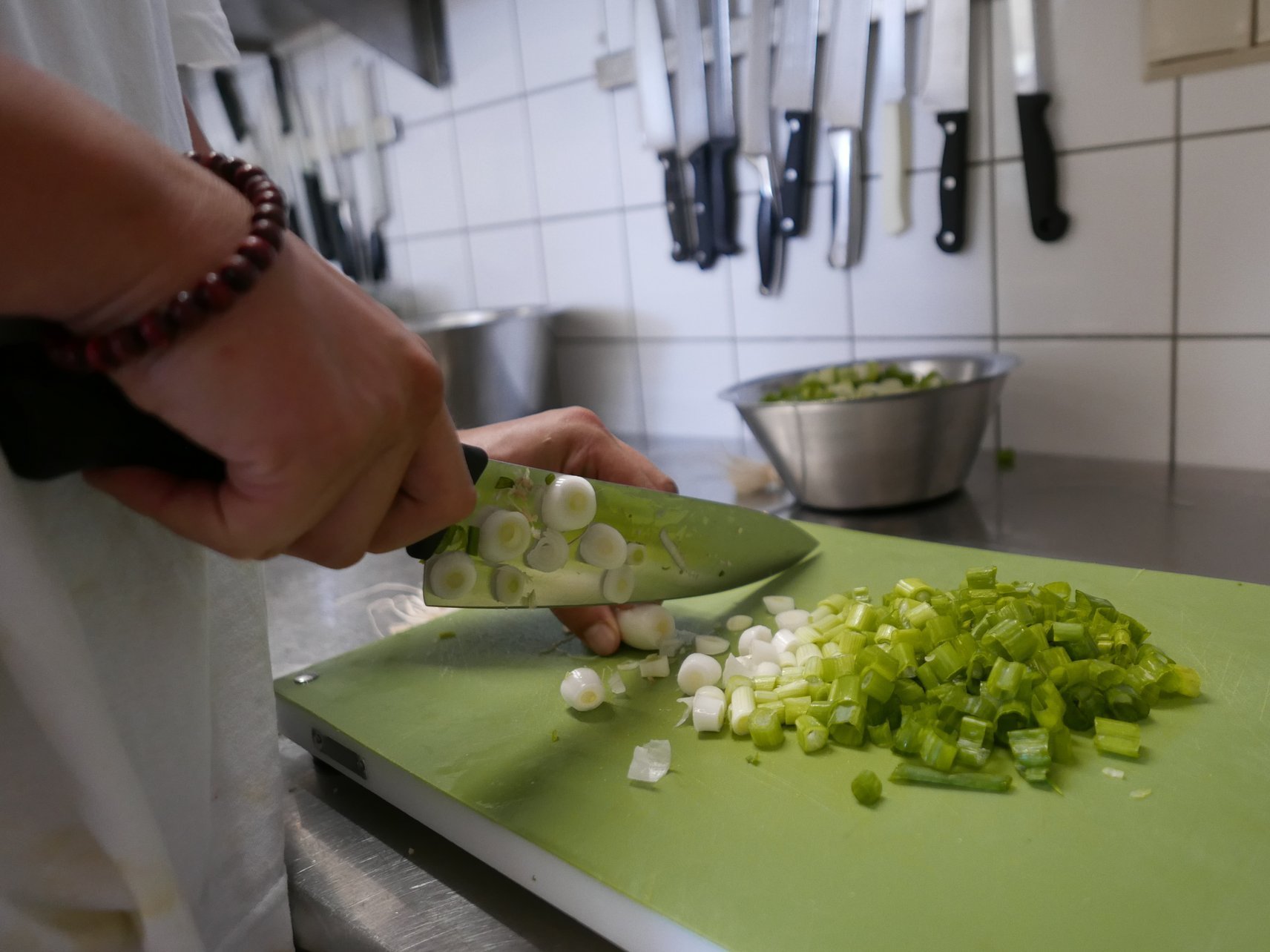 Nahaufnahme: eine Köchen schneidet Lauchzwiebeln