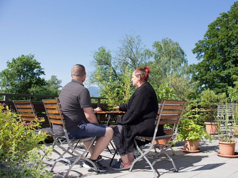 eine Frau und ein Mann sitzen auf der Terasse - unterhalten sich