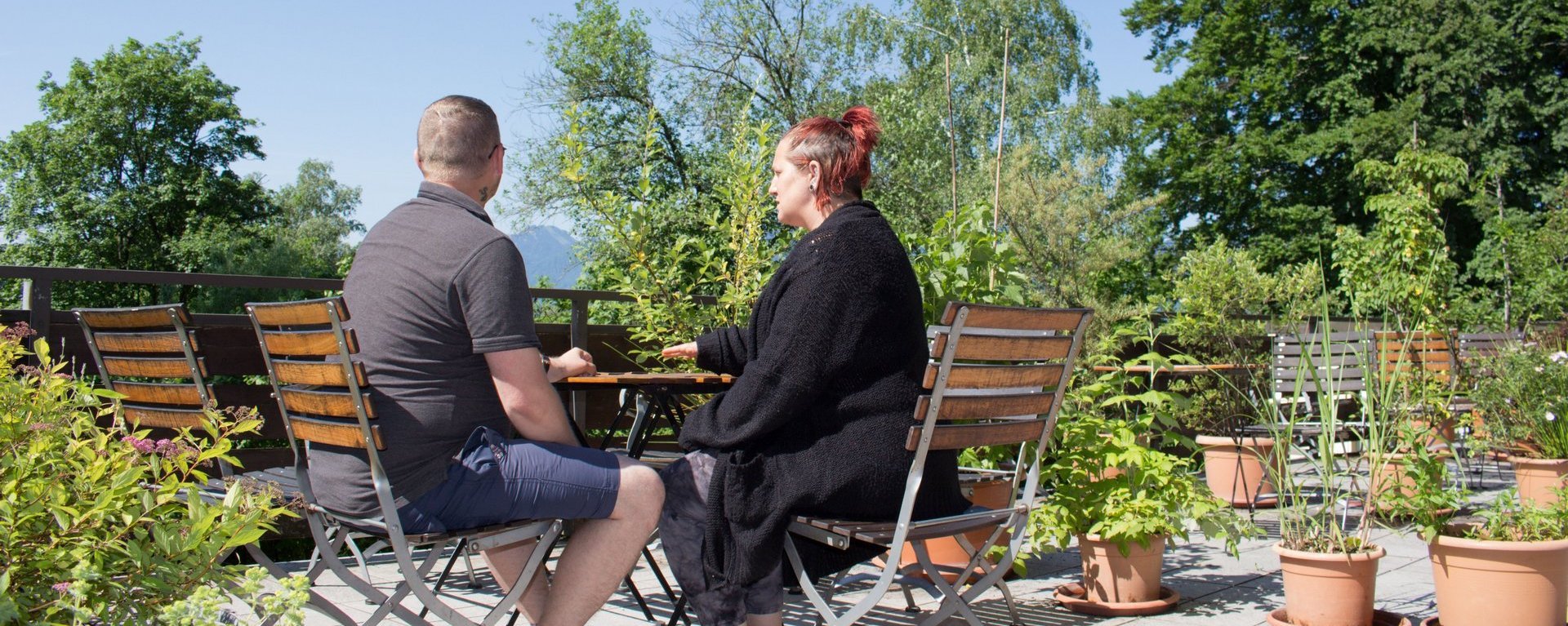 eine Frau und ein Mann sitzen auf der Terasse - unterhalten sich