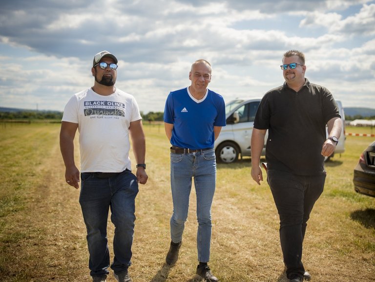 Bei einem Ausflug schlendern drei Männer nebeneinander her.