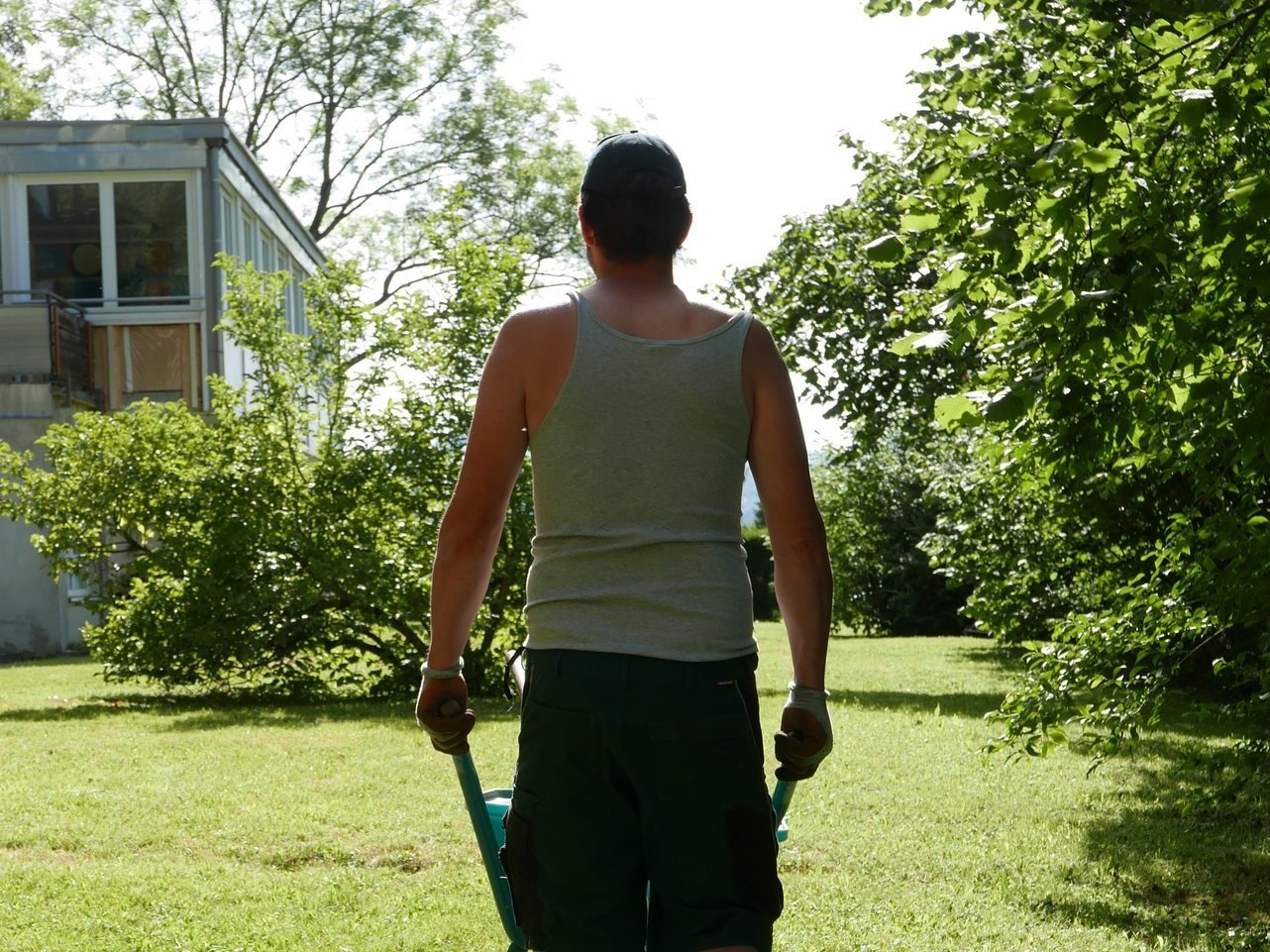 Gartenarbeit am Gebäude: ein Mann schiebt eine Schubkarre